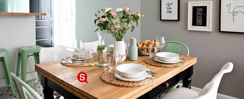 Ein Esszimmer im skandinavischen Stil mit einem Tisch und bunten Stühlen. Holzelemente untermalen den stimmungsvollen Charakter des Innenraums.