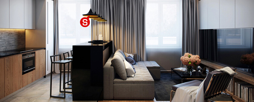 Ein Wohnzimmer im modernen Stil mit einem weißen Sofa und bunten Dekokissen. 
Auf dem schwarzen Couchtisch liegt ein Buch und unter dem Tisch liegt ein moderner grauer Teppich mit weißen Akzenten. 

